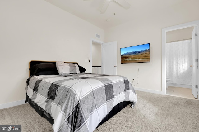 bedroom with ceiling fan, light carpet, visible vents, baseboards, and ensuite bath