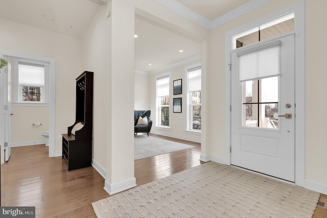 entrance foyer featuring baseboards, crown molding, and light wood finished floors