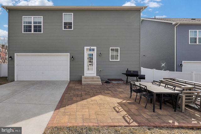 back of property featuring entry steps, a patio, a garage, fence, and outdoor dining space