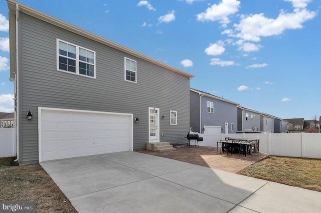 back of house featuring an attached garage, driveway, a patio area, and fence