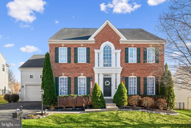 georgian-style home with brick siding, driveway, and a front lawn