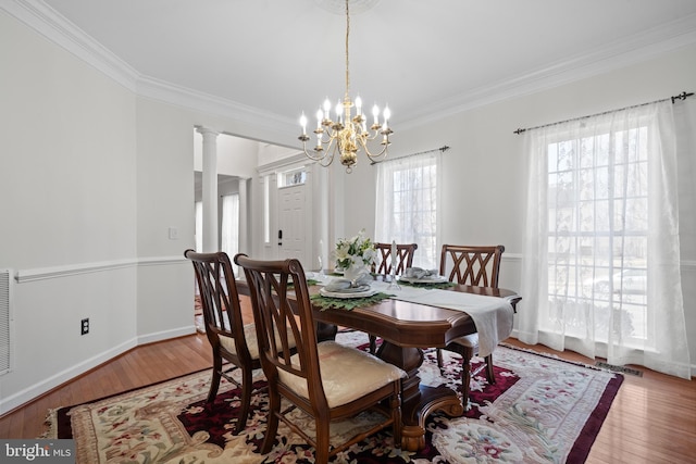 dining area featuring crown molding, decorative columns, and wood finished floors