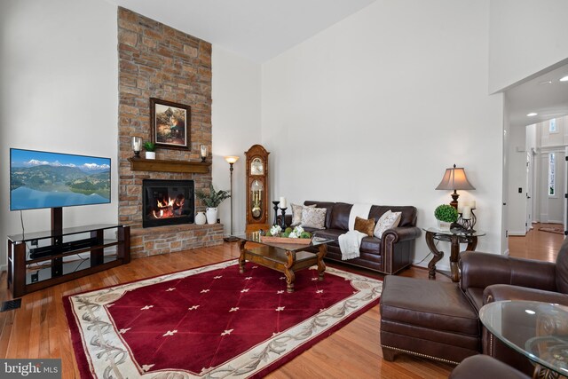 living room featuring a fireplace, a high ceiling, and wood-type flooring