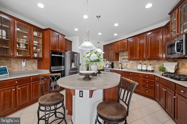 kitchen featuring a breakfast bar area, light tile patterned floors, a kitchen island, a sink, and stainless steel appliances