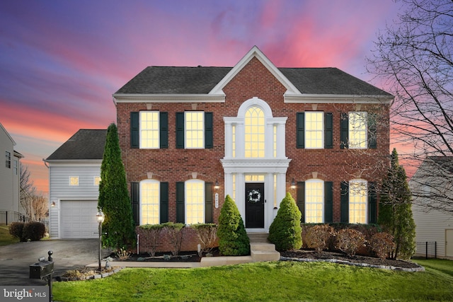 view of front of home with concrete driveway, brick siding, roof with shingles, and a front lawn