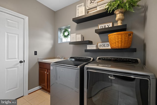 washroom featuring independent washer and dryer, a sink, cabinet space, light tile patterned floors, and baseboards