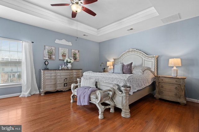 bedroom with visible vents, a raised ceiling, baseboards, and hardwood / wood-style floors