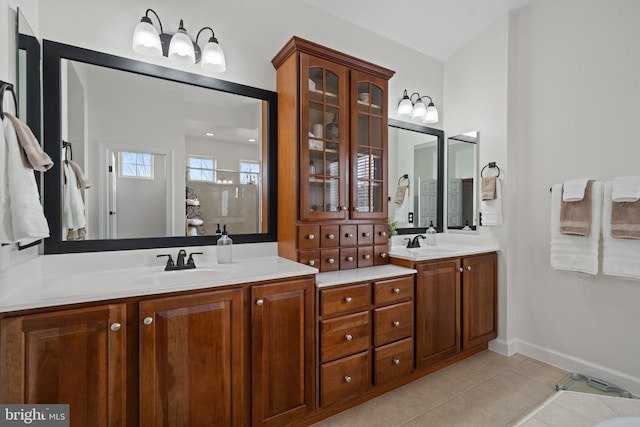 bathroom with a sink, baseboards, double vanity, and tile patterned floors