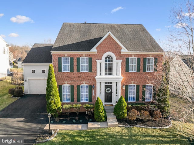 view of front of property featuring brick siding, a shingled roof, fence, a garage, and driveway