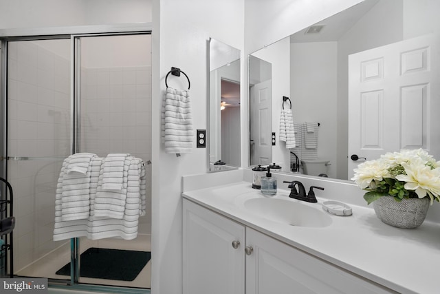 full bathroom featuring vanity, a shower stall, toilet, and visible vents