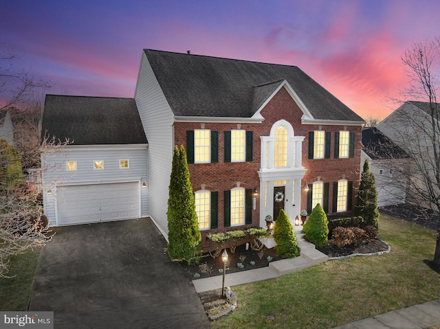 view of front facade featuring a front lawn, aphalt driveway, a shingled roof, a garage, and brick siding