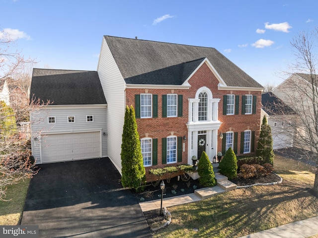 view of front of house featuring a garage, brick siding, driveway, and roof with shingles