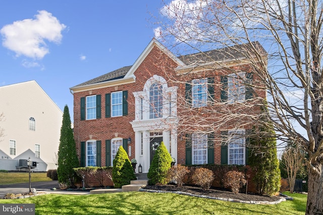 colonial home with brick siding and a front lawn