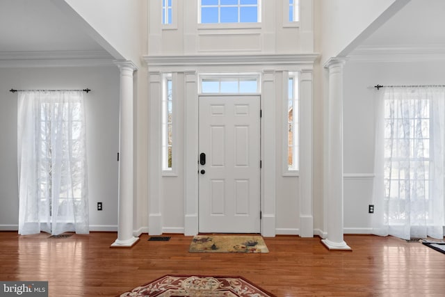 entrance foyer with plenty of natural light, wood finished floors, and decorative columns