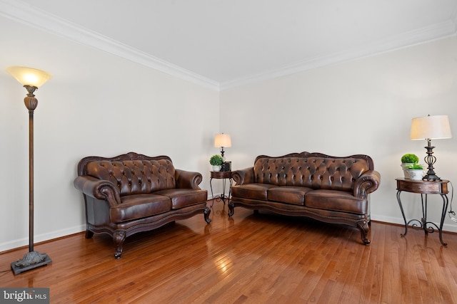 living area with baseboards, hardwood / wood-style floors, and crown molding