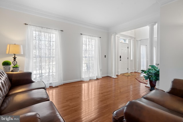 living room with crown molding, hardwood / wood-style flooring, plenty of natural light, and ornate columns