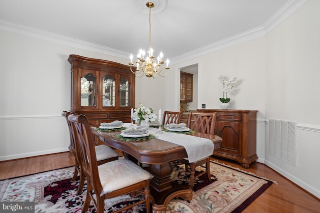 dining area with visible vents, baseboards, ornamental molding, wood finished floors, and a notable chandelier