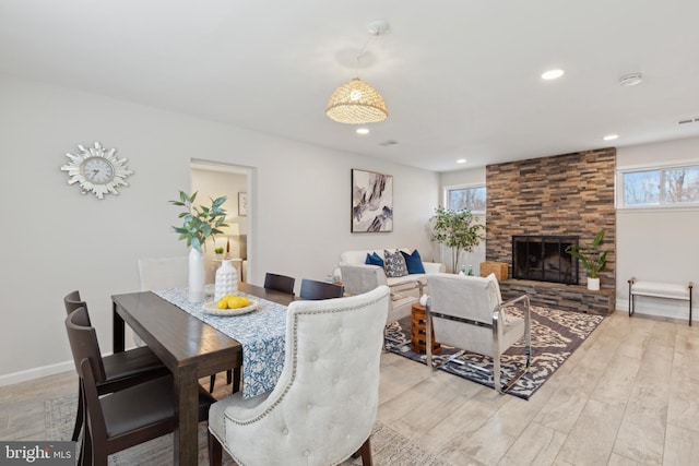 dining room featuring a stone fireplace and light hardwood / wood-style floors