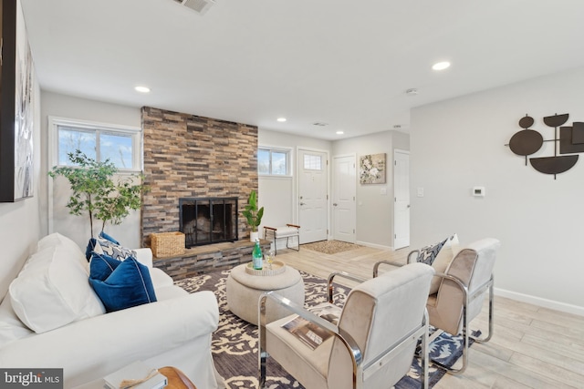 living room featuring a wealth of natural light, a large fireplace, and light wood-type flooring