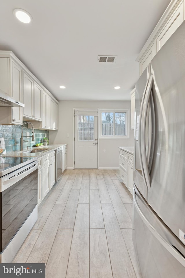 kitchen with white cabinetry, appliances with stainless steel finishes, sink, and decorative backsplash