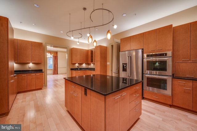 kitchen featuring pendant lighting, stainless steel appliances, a center island, and light hardwood / wood-style floors