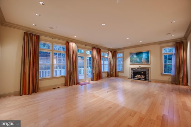 unfurnished living room featuring ornamental molding, a premium fireplace, and light hardwood / wood-style flooring