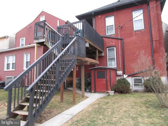 rear view of house with a yard, brick siding, and stairway