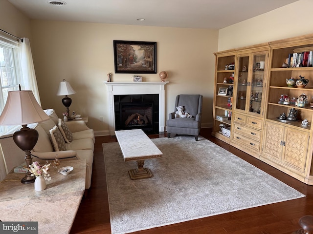 living room featuring a tile fireplace and dark hardwood / wood-style floors