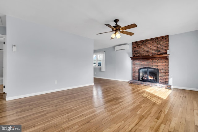 unfurnished living room with ceiling fan, light hardwood / wood-style flooring, a wall mounted AC, and a brick fireplace