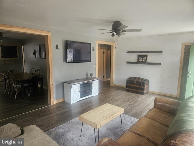 living room featuring dark wood-type flooring and ceiling fan