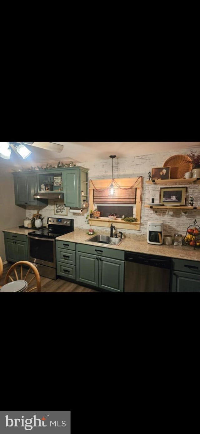 kitchen featuring appliances with stainless steel finishes, decorative light fixtures, sink, backsplash, and green cabinets