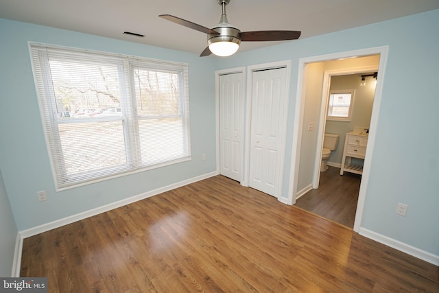 unfurnished bedroom with multiple windows, wood-type flooring, and multiple closets