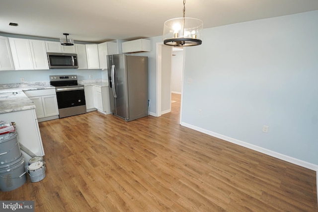 kitchen with a chandelier, hanging light fixtures, stainless steel appliances, light hardwood / wood-style floors, and white cabinets