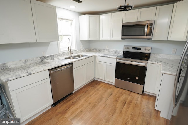 kitchen with light wood-type flooring, appliances with stainless steel finishes, sink, and white cabinets