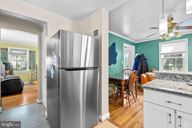 kitchen featuring light hardwood / wood-style floors, stainless steel refrigerator, white cabinets, and stone counters