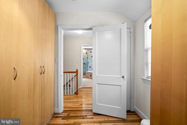 hallway with vaulted ceiling and light wood-type flooring