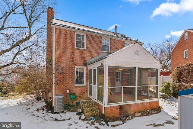 snow covered house with a sunroom and central AC unit