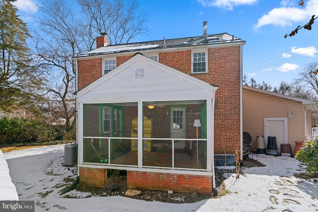 snow covered rear of property featuring a sunroom and cooling unit