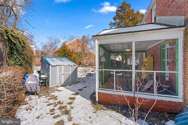 view of snow covered exterior featuring a shed and a sunroom