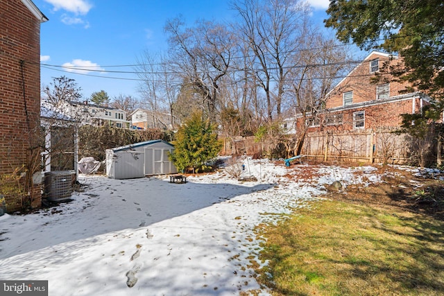 yard layered in snow featuring central AC unit and a shed