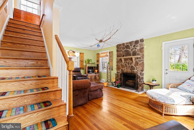 living room featuring a stone fireplace, plenty of natural light, and hardwood / wood-style floors