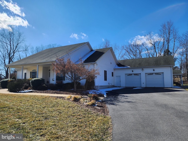 single story home featuring a garage, aphalt driveway, a porch, and a front yard