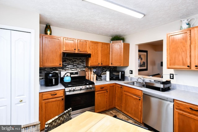 kitchen featuring sink, backsplash, stainless steel appliances, and a textured ceiling