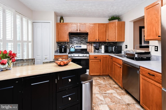 kitchen featuring stainless steel gas stove, tasteful backsplash, dishwasher, exhaust hood, and a textured ceiling