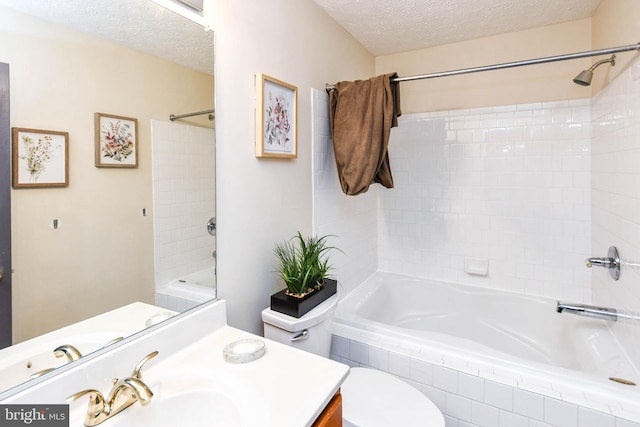 full bathroom featuring vanity, toilet, tiled shower / bath combo, and a textured ceiling