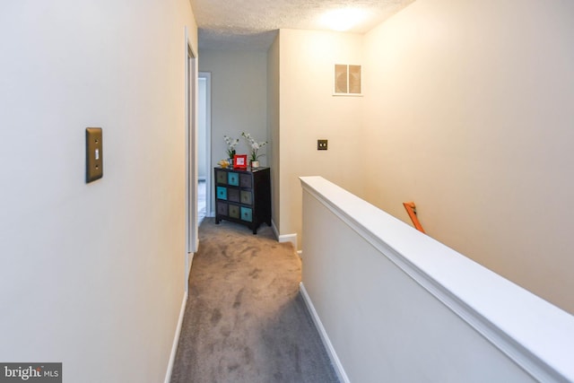 hallway with carpet and a textured ceiling