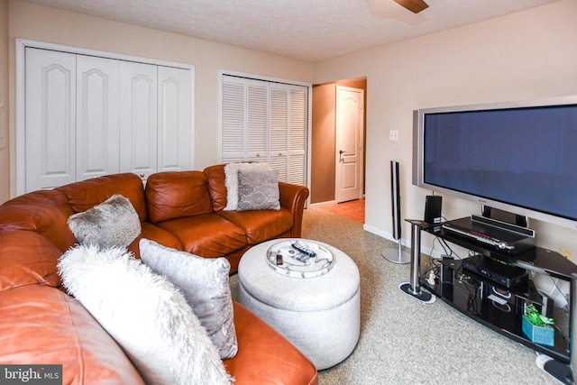 living room featuring ceiling fan, carpet flooring, and a textured ceiling