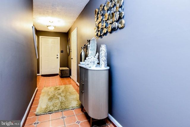 hall featuring light tile patterned flooring and a textured ceiling