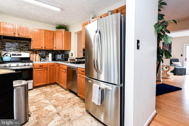 kitchen featuring stainless steel appliances, sink, backsplash, and a textured ceiling