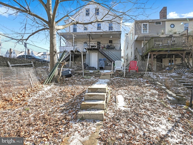 snow covered back of property with a wooden deck